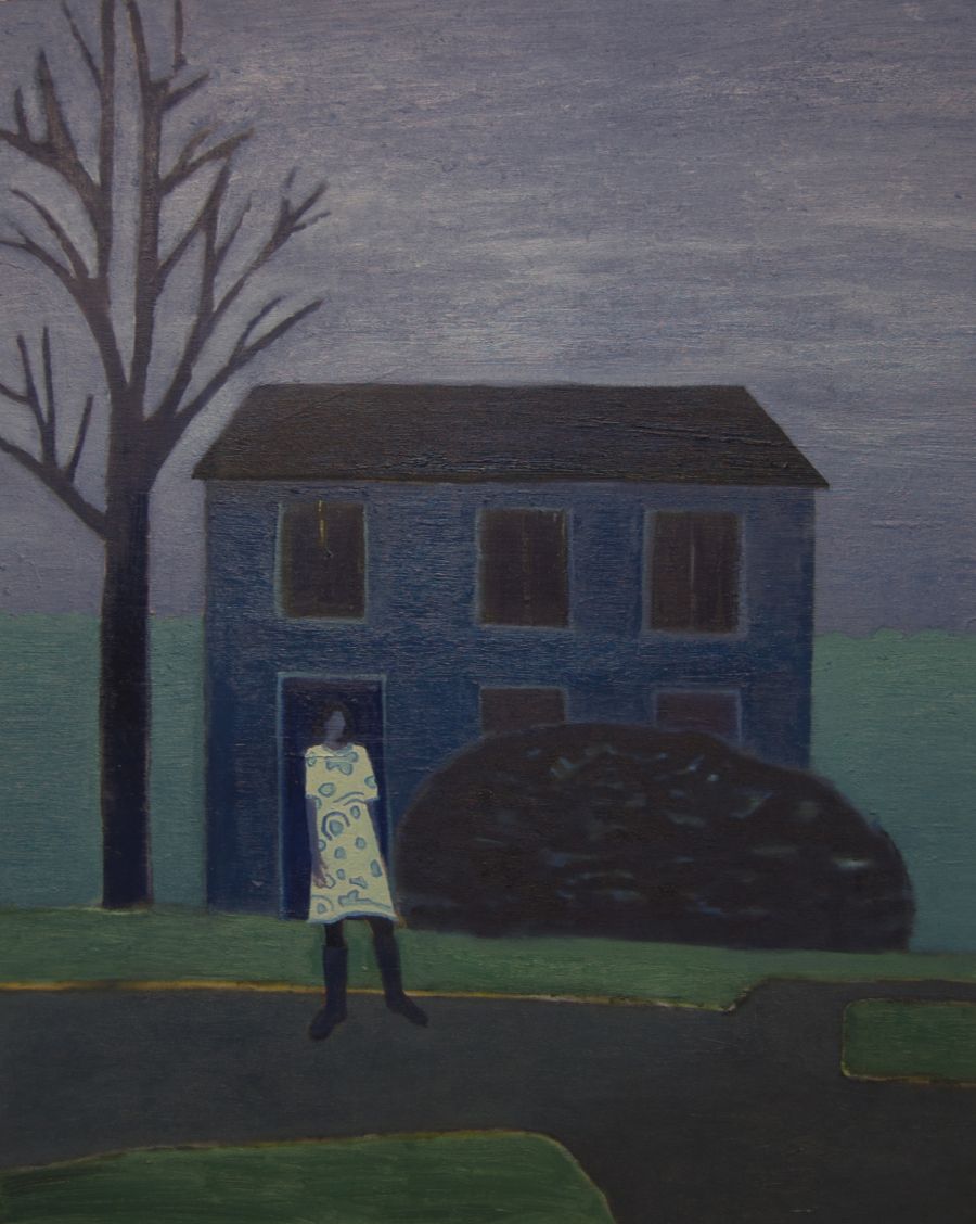 A woman standing on a road outside a blue house.